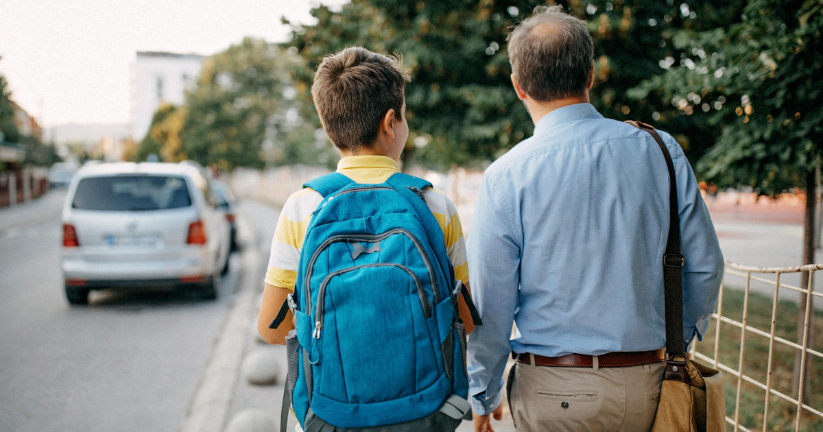 Dad and son with backpack walking to school